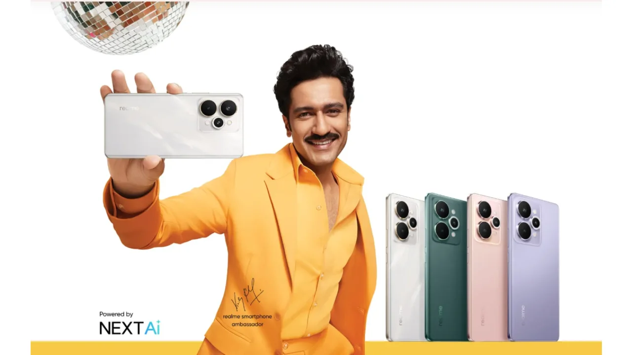 विक्की कौशल सफेद Realme 15 Pro 5G फोन पकड़े हुए हैं, साथ में अन्य रंग (हरा, गुलाबी, बैंगनी) के वेरिएंट भी उनके बगल में प्रदर्शित हैं।